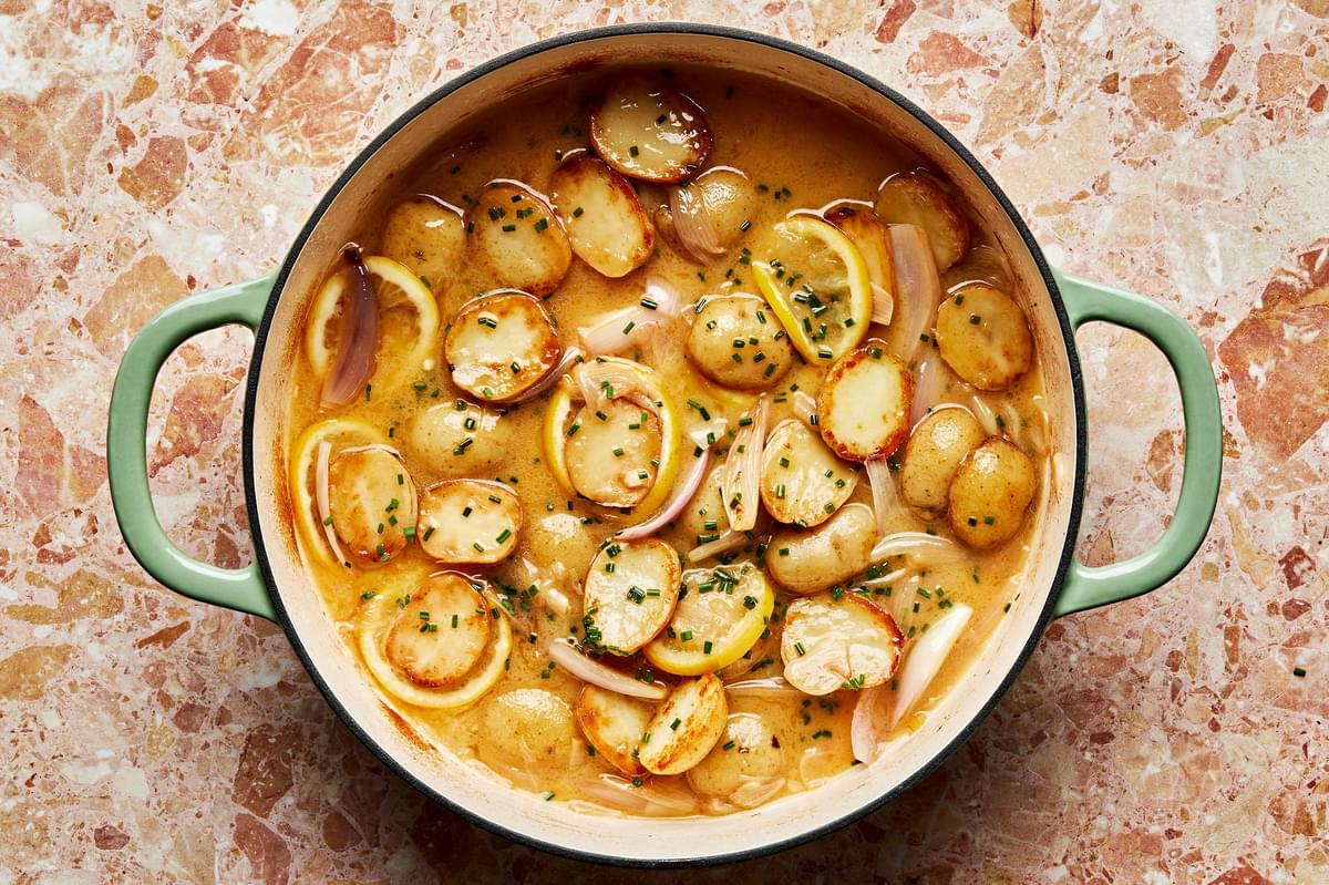 Roasted potatoes and shallots in a braising dish with with a lemon and chive butter sauce