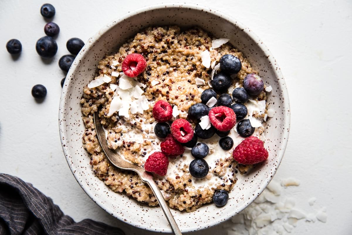 quinoa for breakfast recipe made with coconut milk, maple syrup, vanilla, salt and fresh berries in a bowl