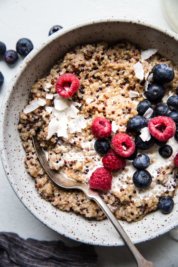 breakfast quinoa made with coconut milk, maple syrup, vanilla, salt and fresh berries in a bowl