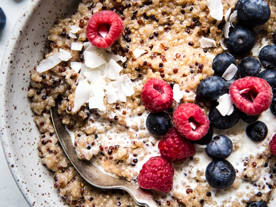 breakfast quinoa made with coconut milk, maple syrup, vanilla, salt and fresh berries in a bowl