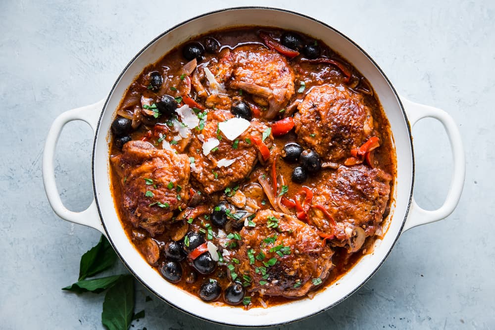 the best chicken cacciatore in a braiser with shallots, olives, bell peppers, basil and parmesan