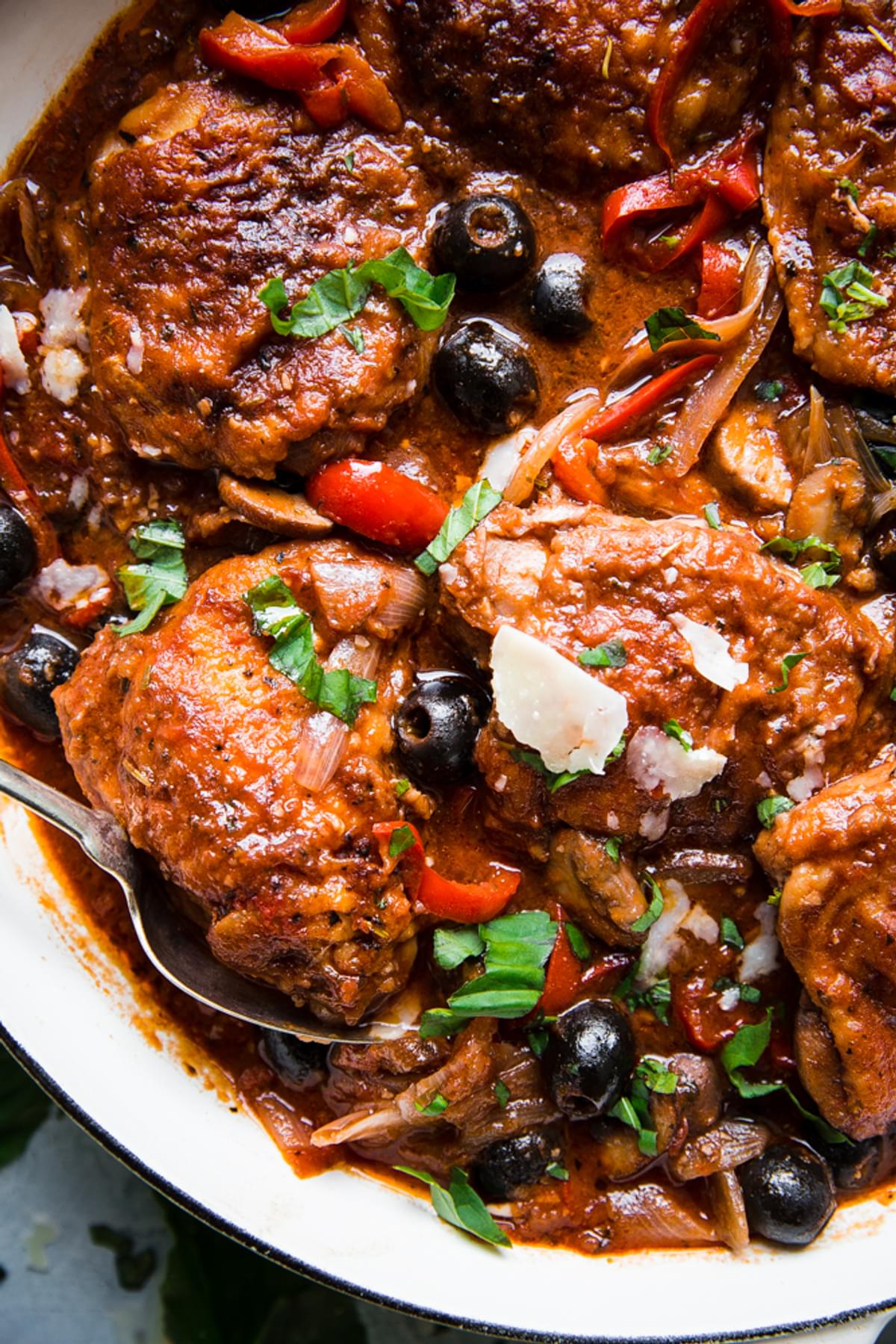 the best chicken cacciatore in a braiser with shallots, olives, bell peppers, basil and parmesan