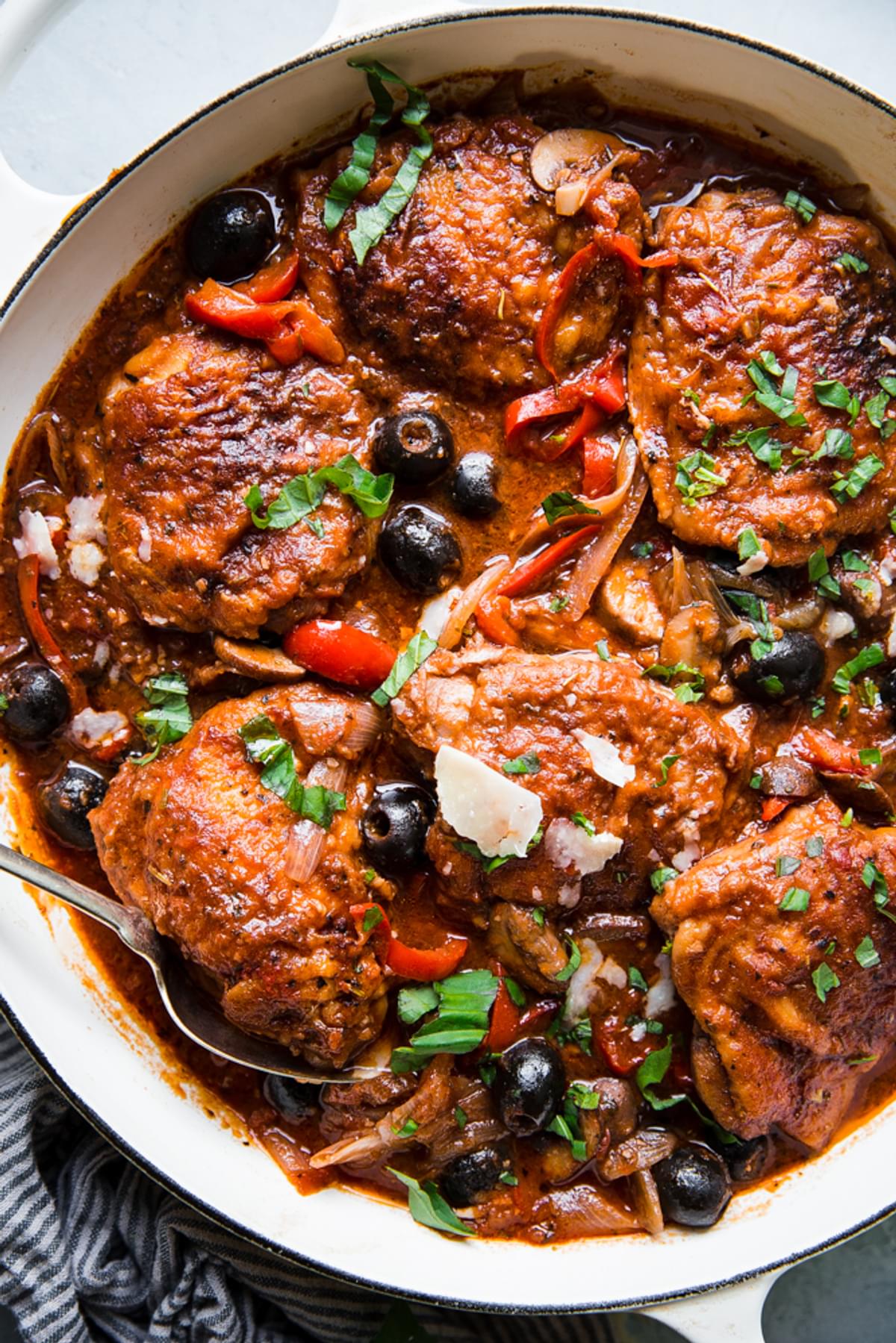 Chicken Cacciatore in a braiser with shallots, olives, bell peppers, basil and parmesan