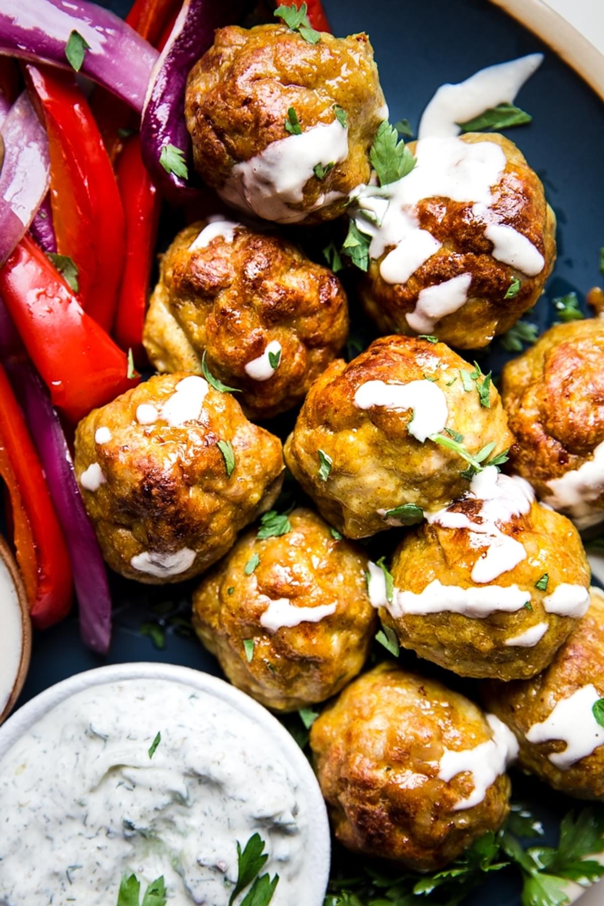 chicken shawarma meatballs shown on a plate drizzled with tahini sauce