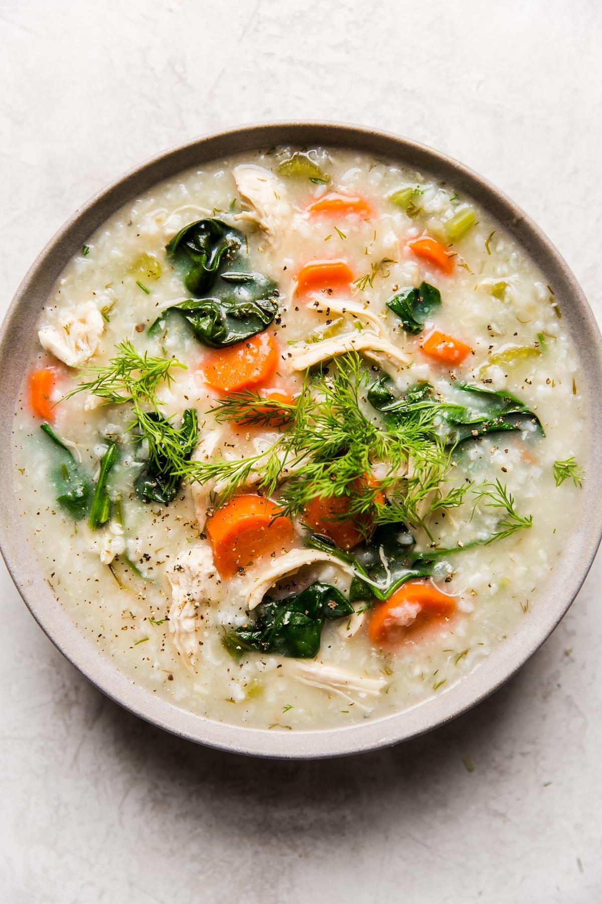 Chicken and rice soup with carrots, spinach, dill and lemon in a bowl