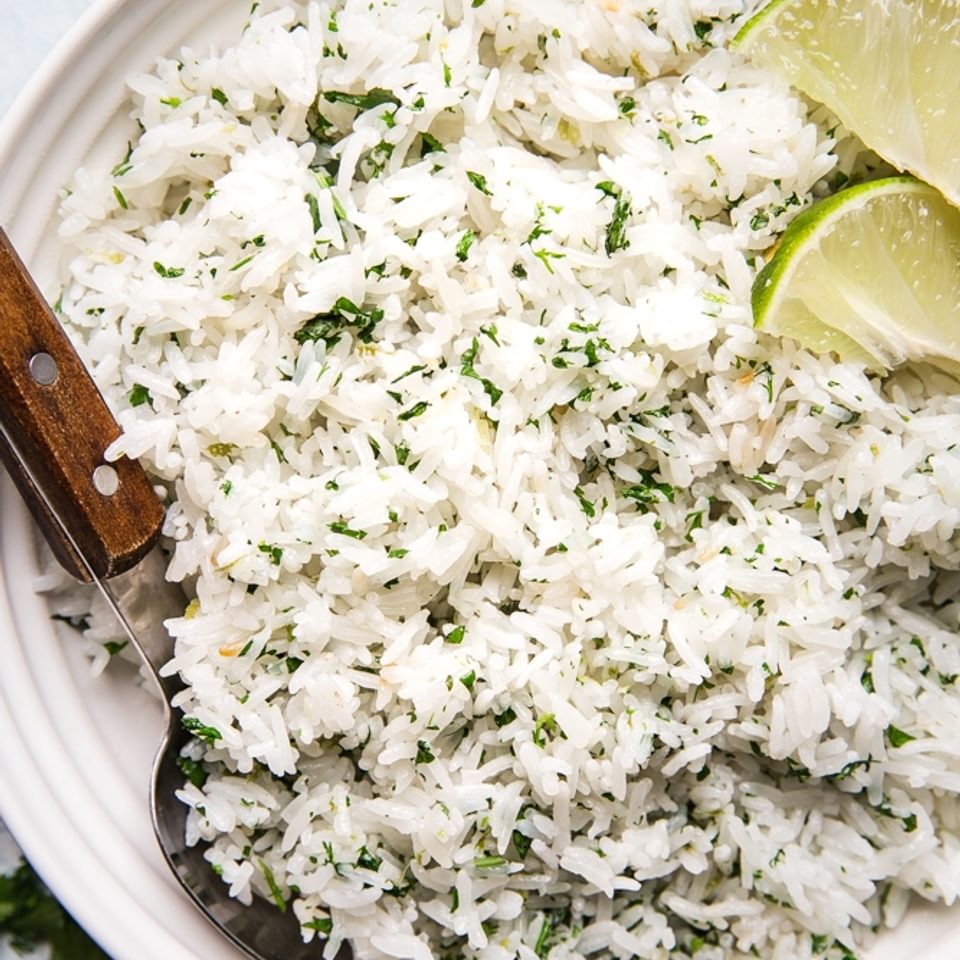 homemade cilantro lime rice in a bowl with a wooden spoon