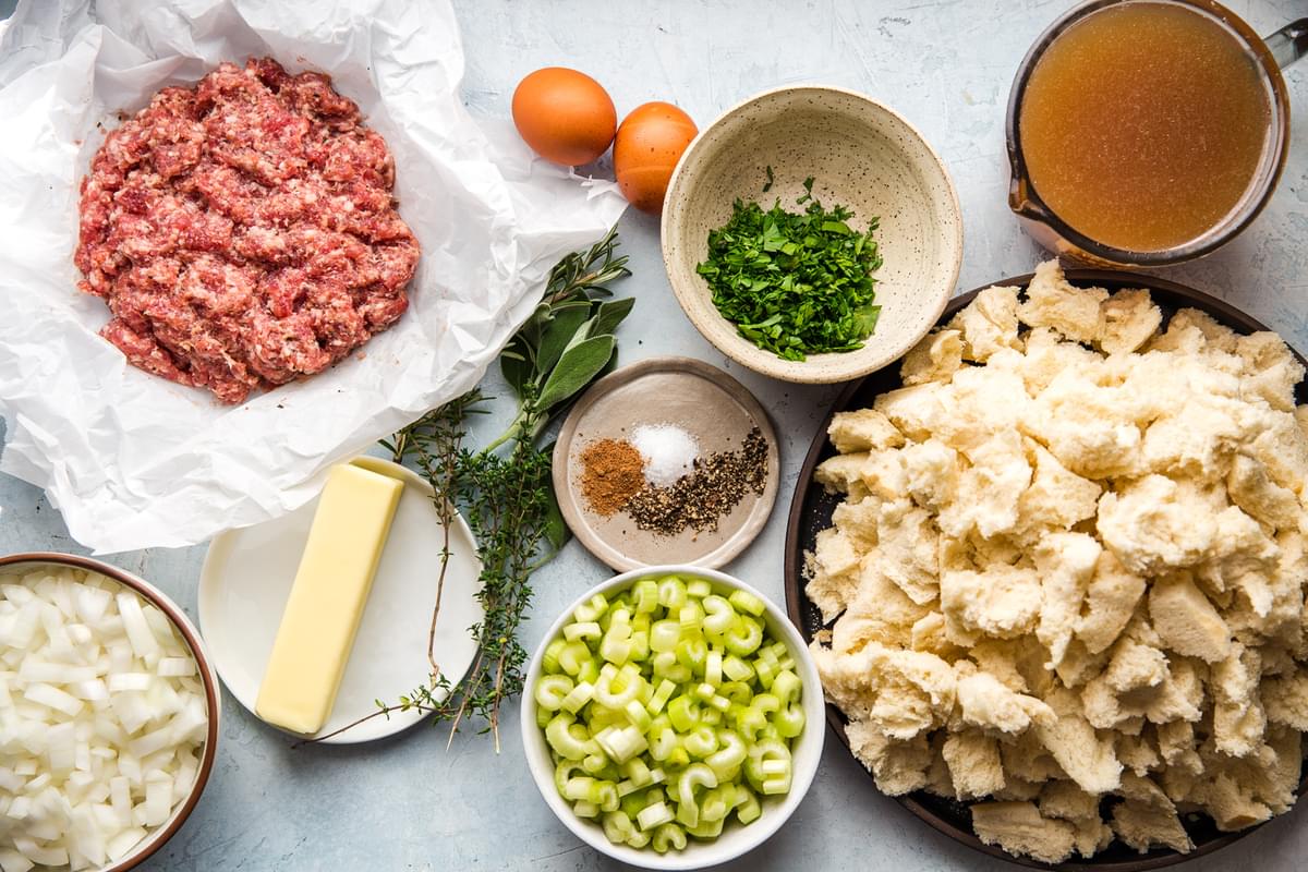 ingredients laid out for classic sausage stuffing, bread, chicken stock, celery, parsley, onion, butter, eggs