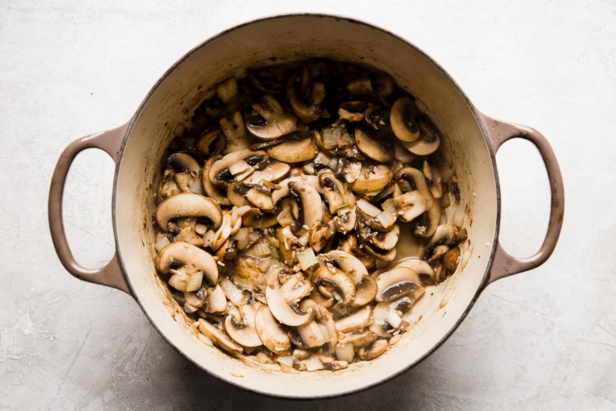sliced mushrooms, butter and garlic cooking in a soup pot