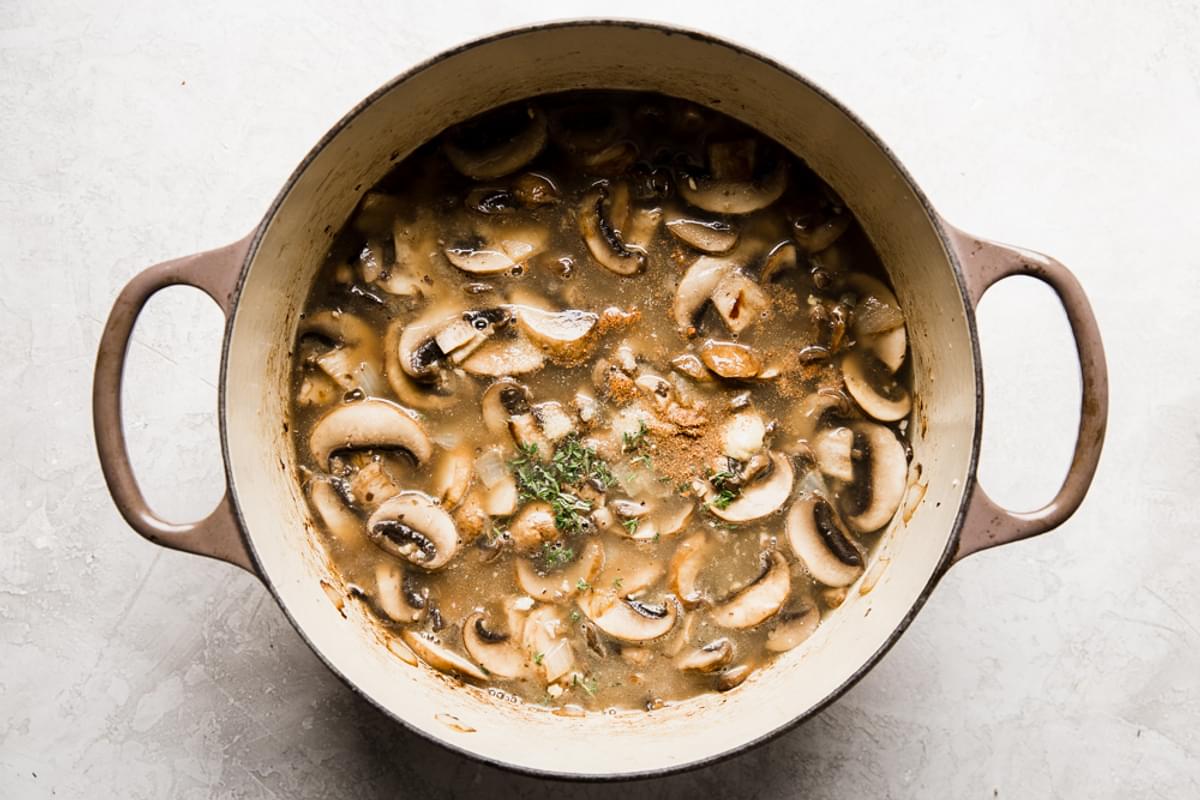 sliced mushrooms, butter, garlic, broth, thyme and onions cooking in a soup pot