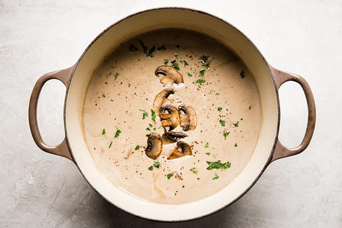 a pot of homemade cream of mushroom soup made with heavy cream and parsley