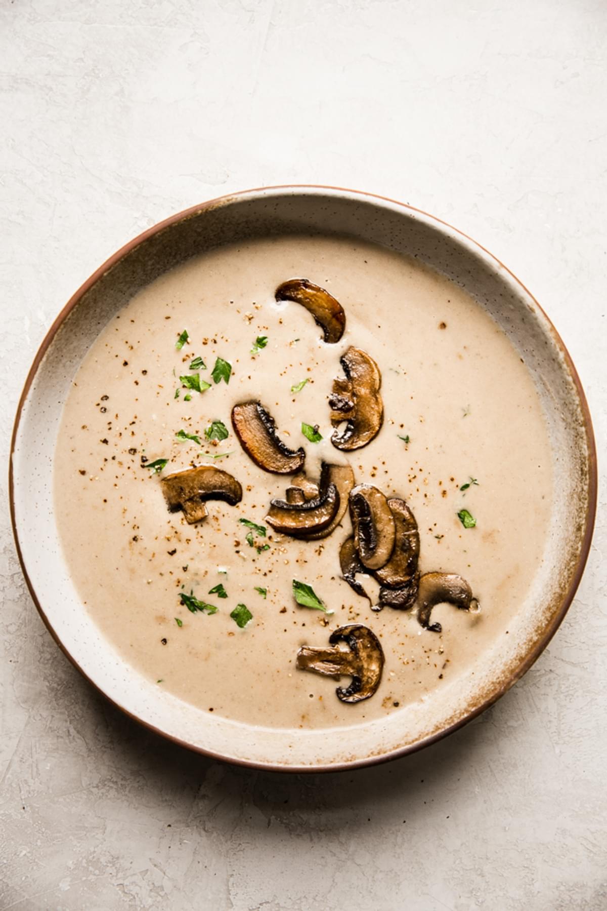a bowl of homemade cream of mushroom soup with heavy cream parsley, onions and garlic