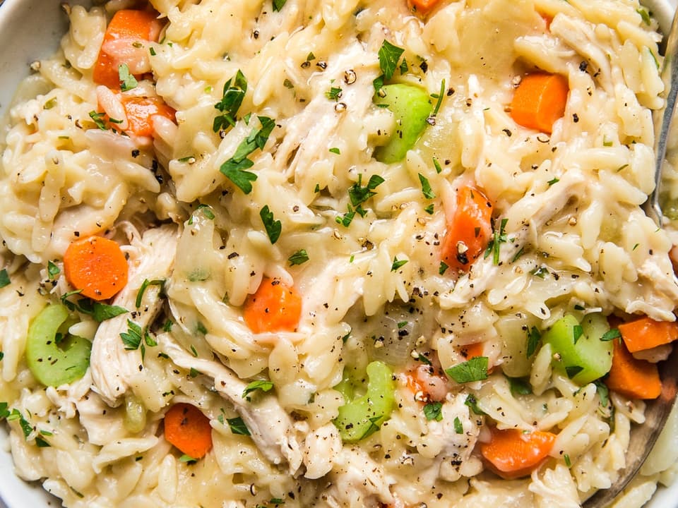 creamy chicken orzo with carrots, celery, onions and garlic  in  a bowl