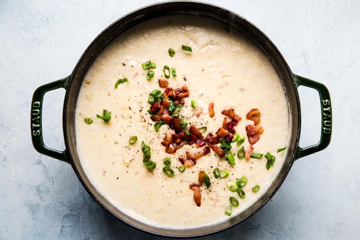 old fashioned potato soup with bacon, cheddar cheese, leeks and green onions in a soup pot
