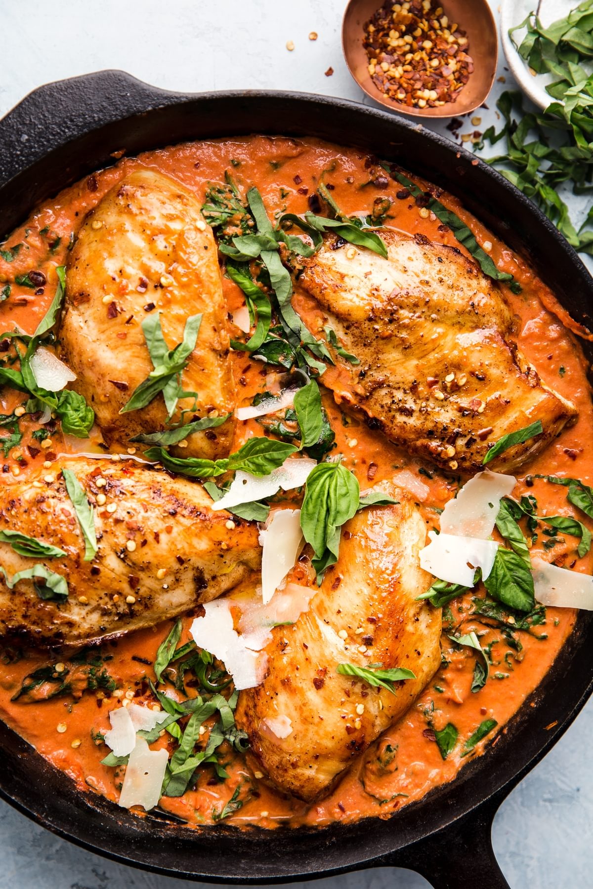 4 chicken breasts cooked in a Creamy Tomato sauce topped with basil and parmesan cheese in a cast iron skillet