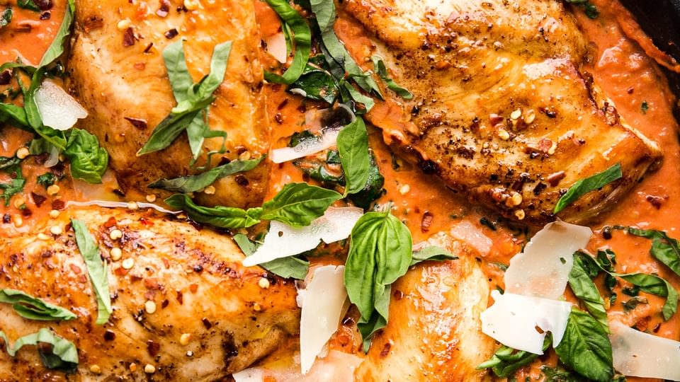 4 chicken breasts cooked in a Creamy Tomato sauce topped with basil and parmesan cheese in a cast iron skillet