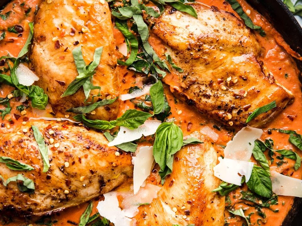 Creamy Tomato Chicken Skillet with basil and parmesan cheese in a cast iron skillet