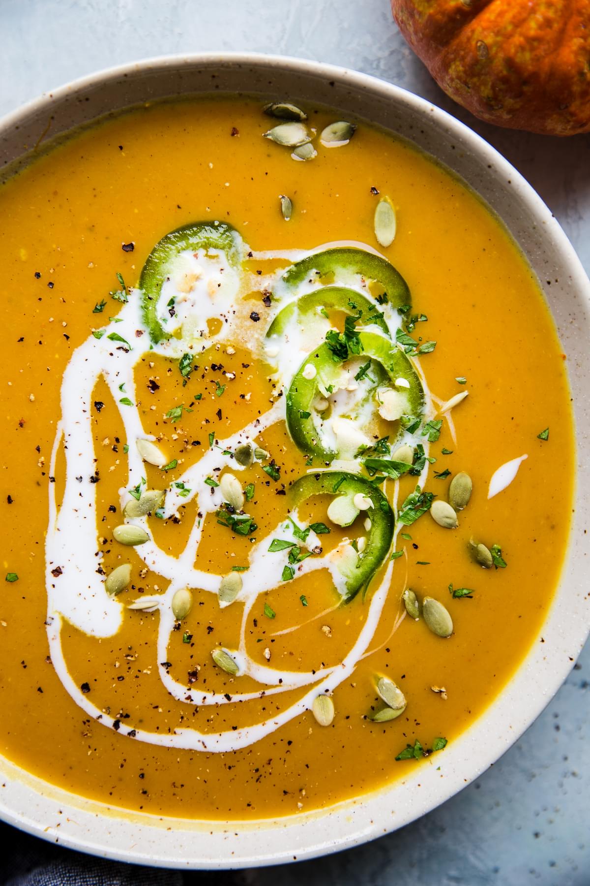 curried pumpkin soup topped with coconut milk, pumpkin seeds, slivered jalapenos and black pepper