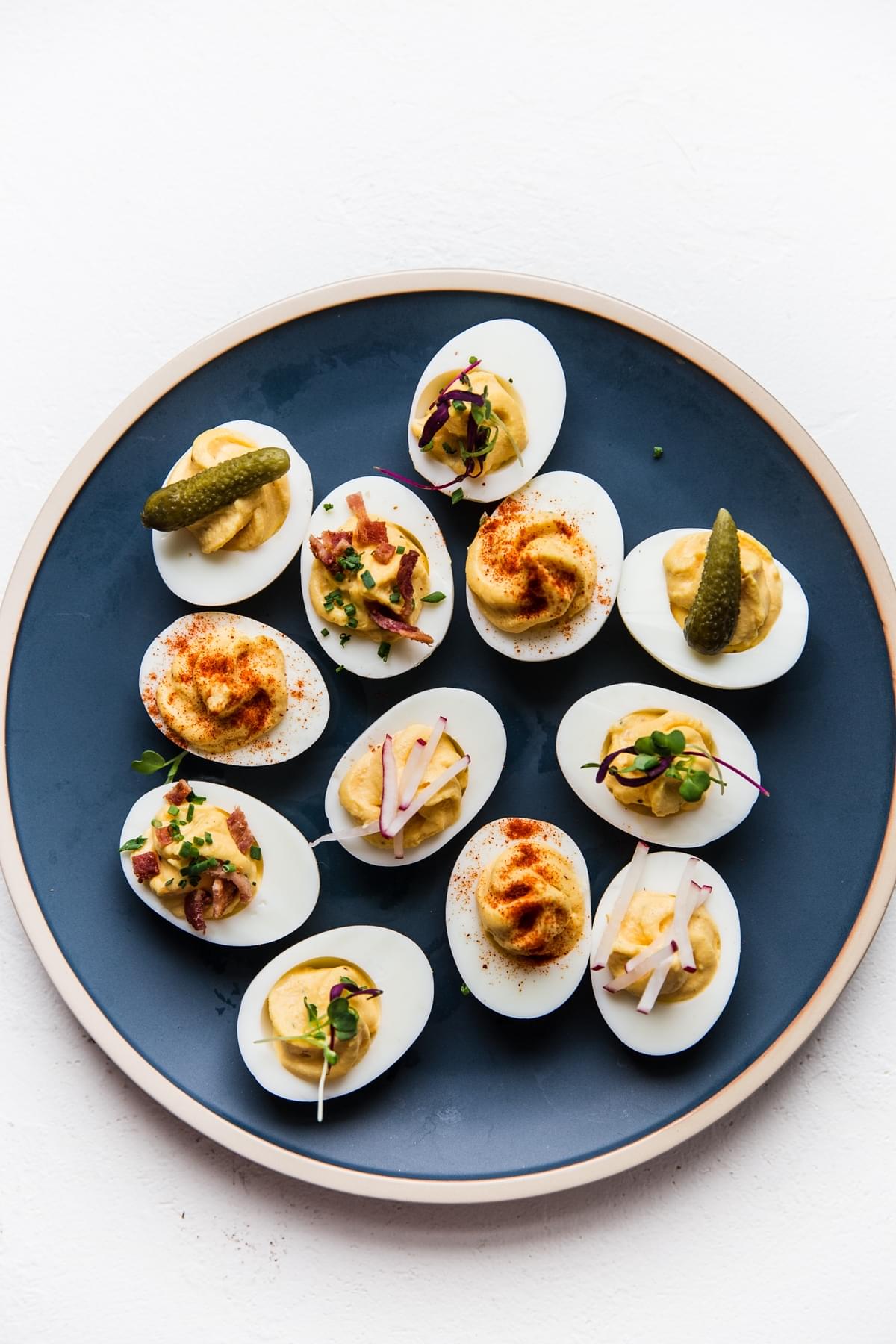 homemade deviled eggs on a blue plate topped with various toppings