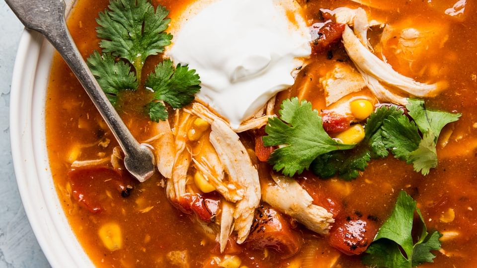 5 ingredient chicken tortilla soup in a bowl with cilantro and sour cream