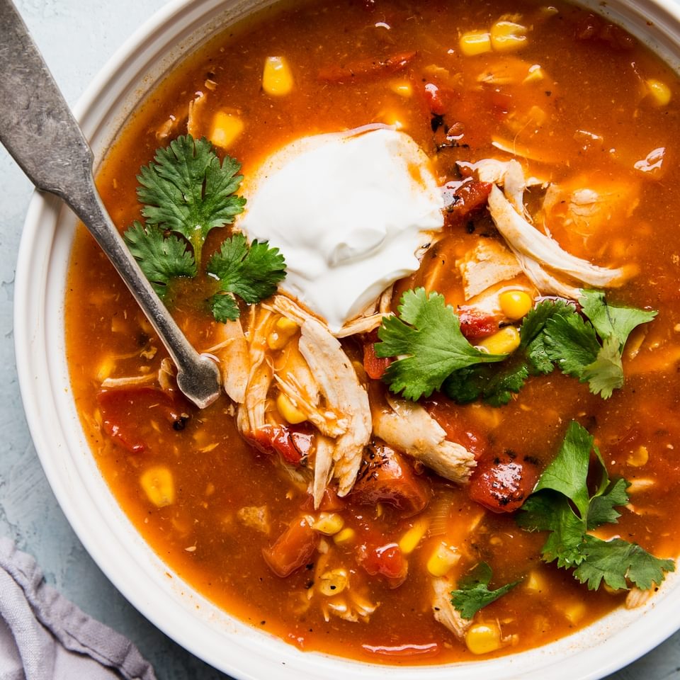 5 ingredient chicken tortilla soup in a bowl with cilantro and sour cream