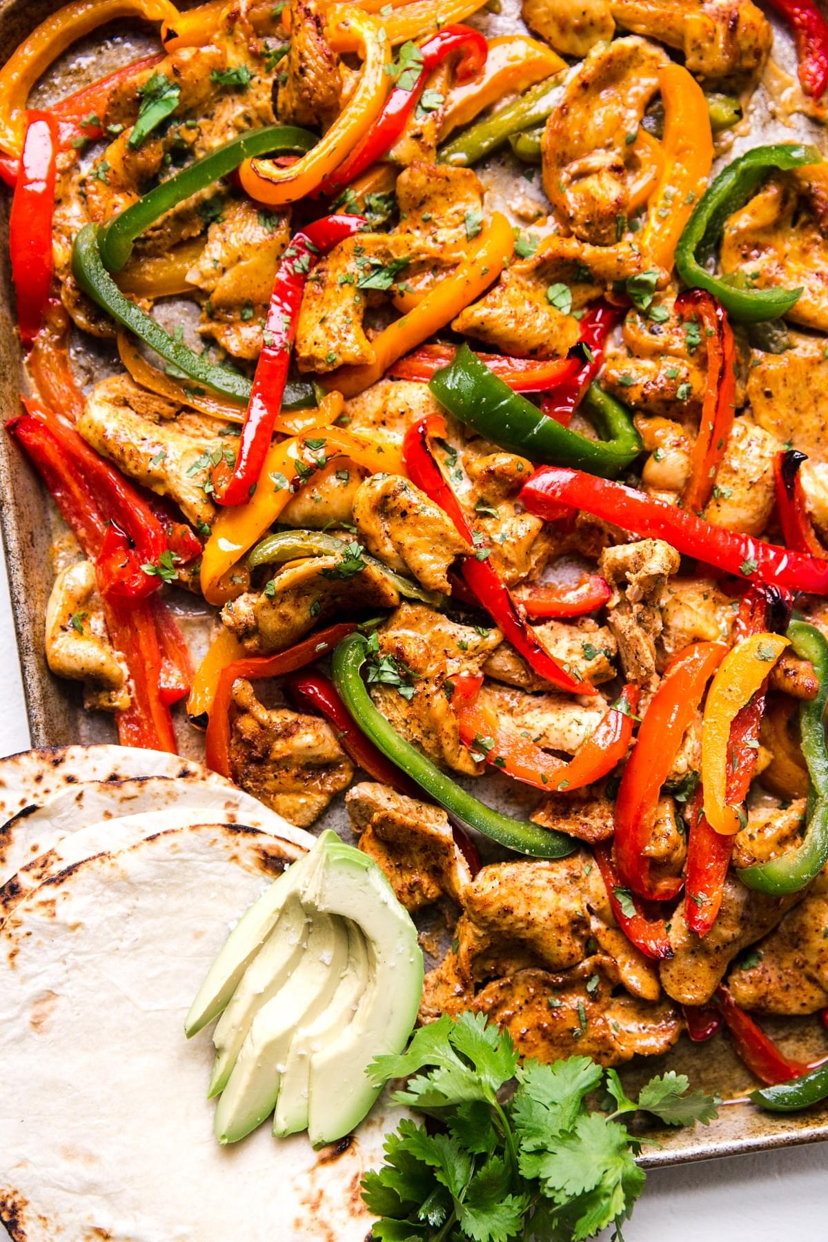 freezer chicken fajita meal on a sheet pan for dinner with tortillas and avocado and bell peppers