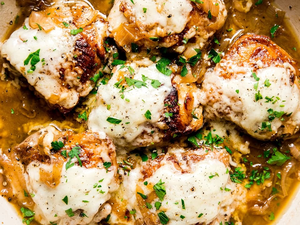 French onion chicken in a braiser with gruyere cheese and caramelized onions