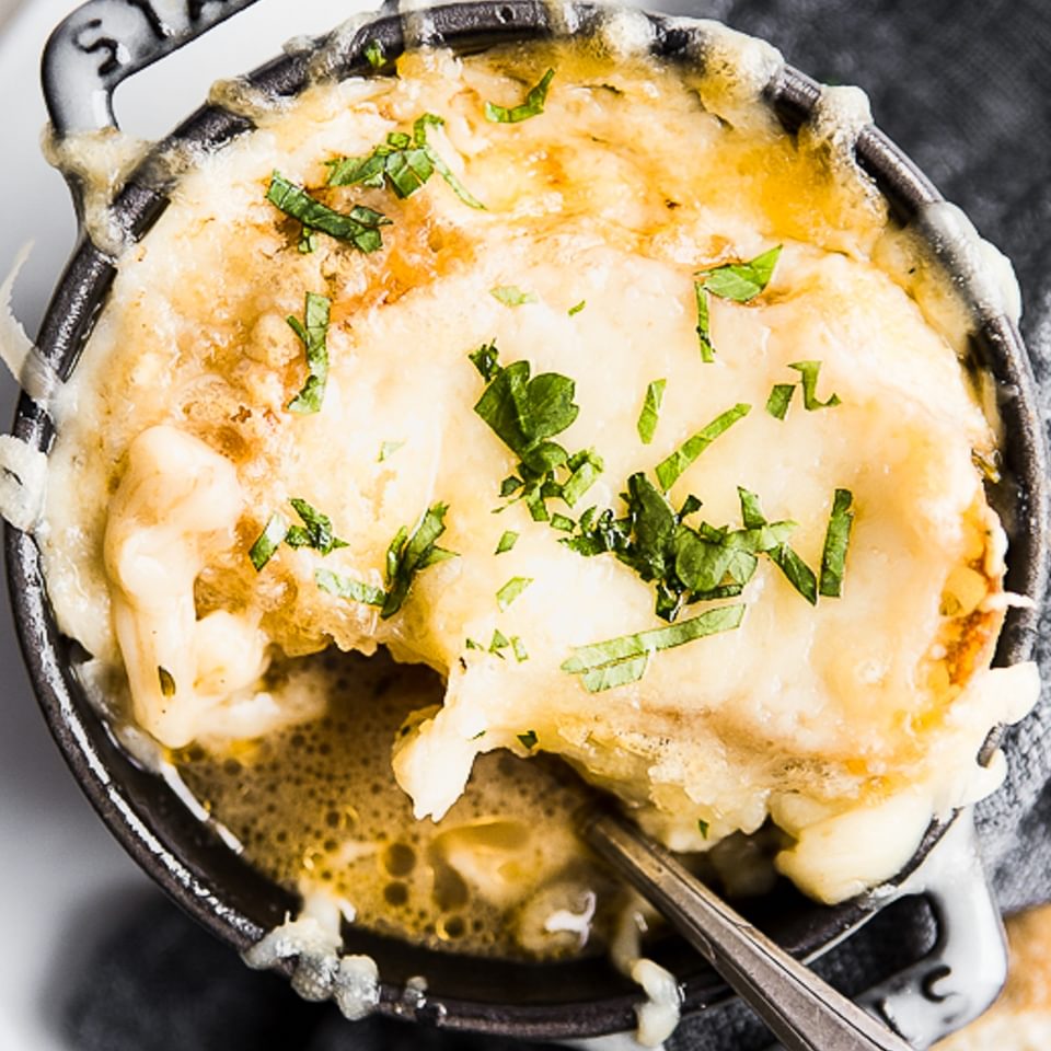 French Onion Soup in a cocotte with melted gruyere cheese and caramelized onions.