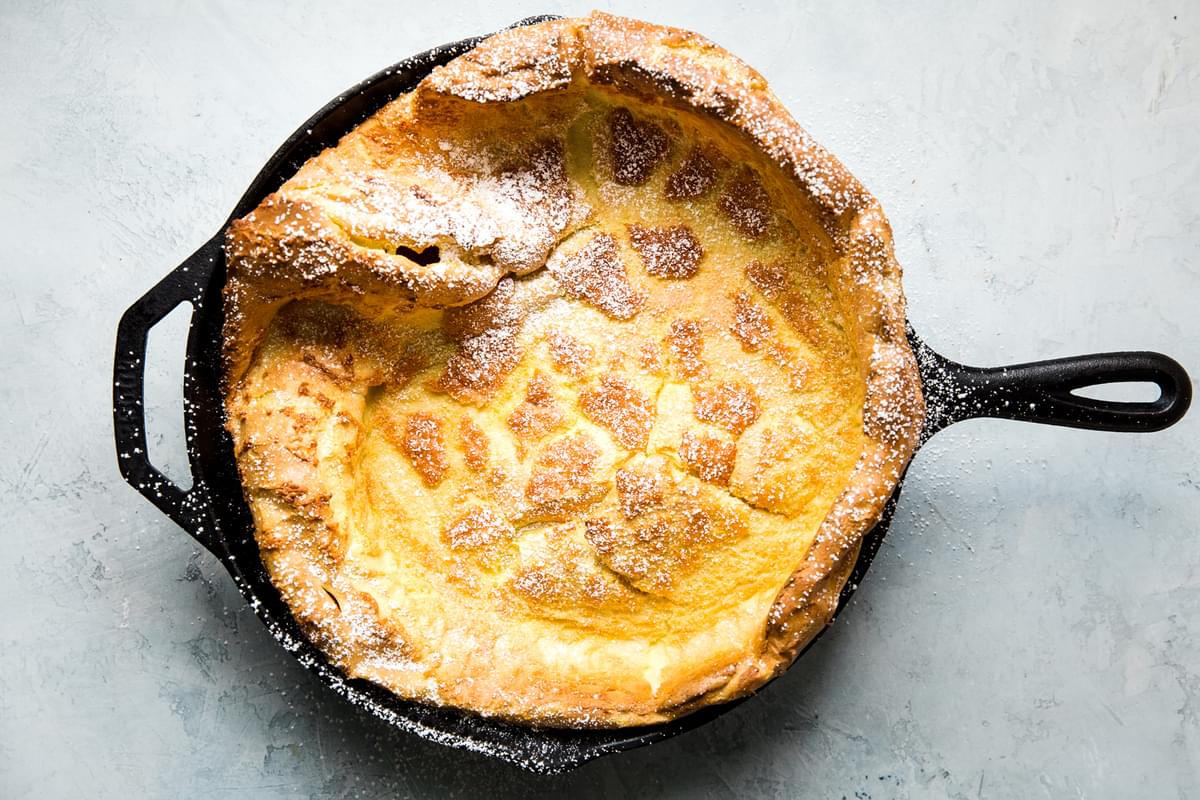 Dutch Baby pancake fresh out of the oven in a cast iron skillet with powdered sugar