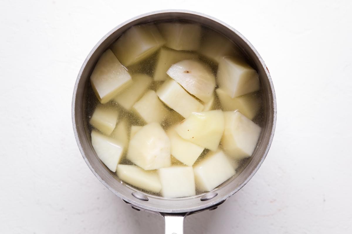Chunks of potatoes being boiled in a small pot