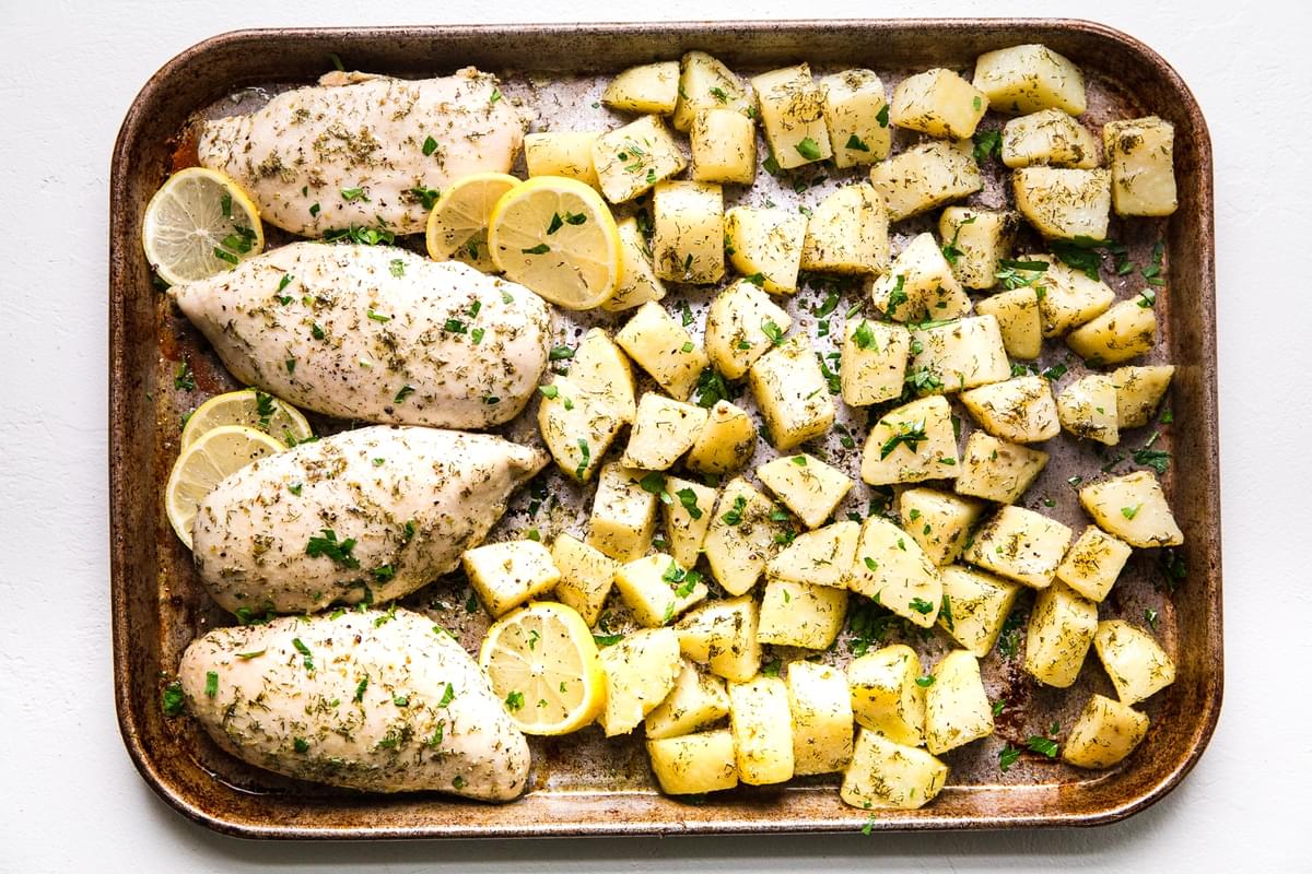 Roasted lemon chicken on a baking sheet with potatoes and spices freezer sheet pan meal