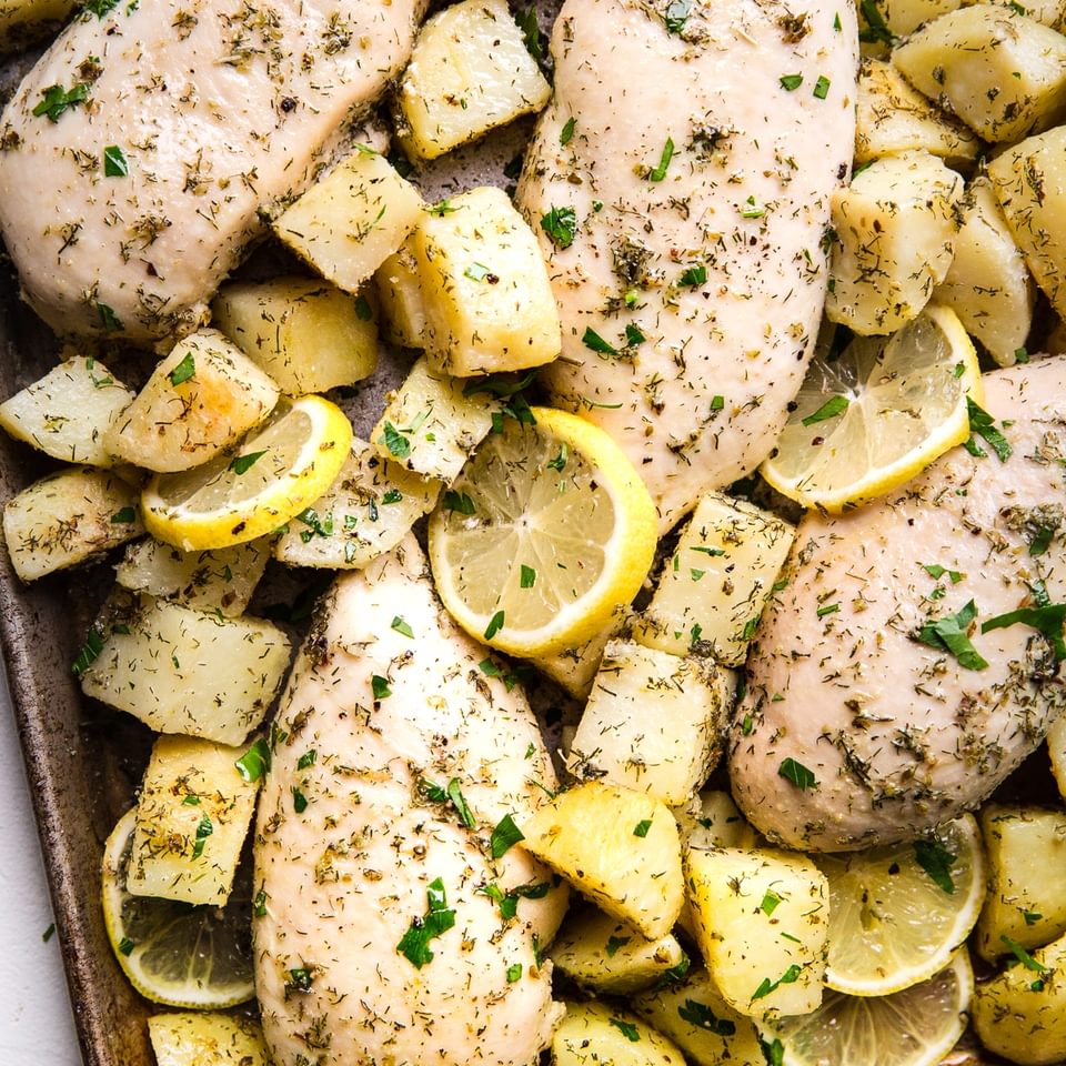 4 Greek flavored Chicken breast with potatoes, olive oil, lemon oregano, garlic, dill on a sheet pan.