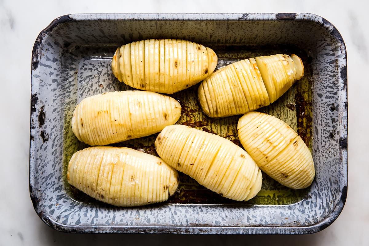 6 roasted hasselback potatoes in a baking dish brushed with garlic butter