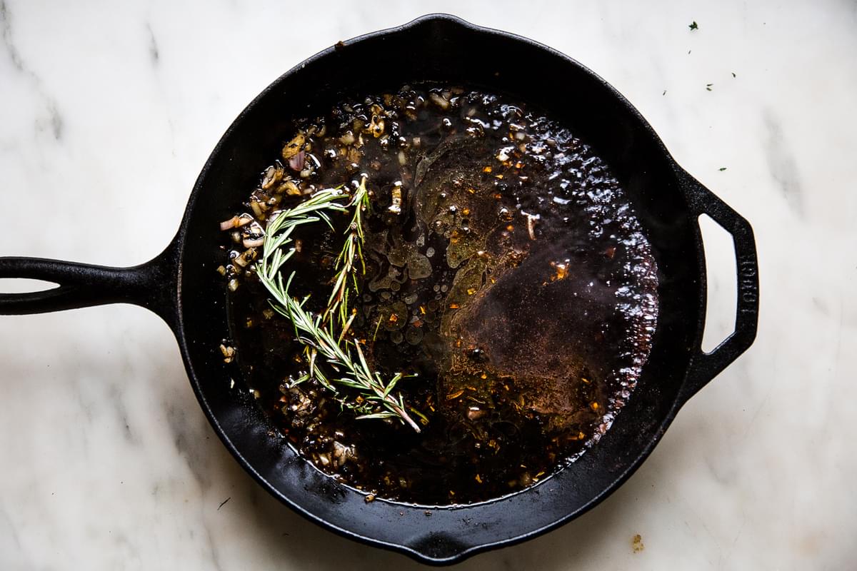 fresh rosemary in a pan with dripping from a pork roast