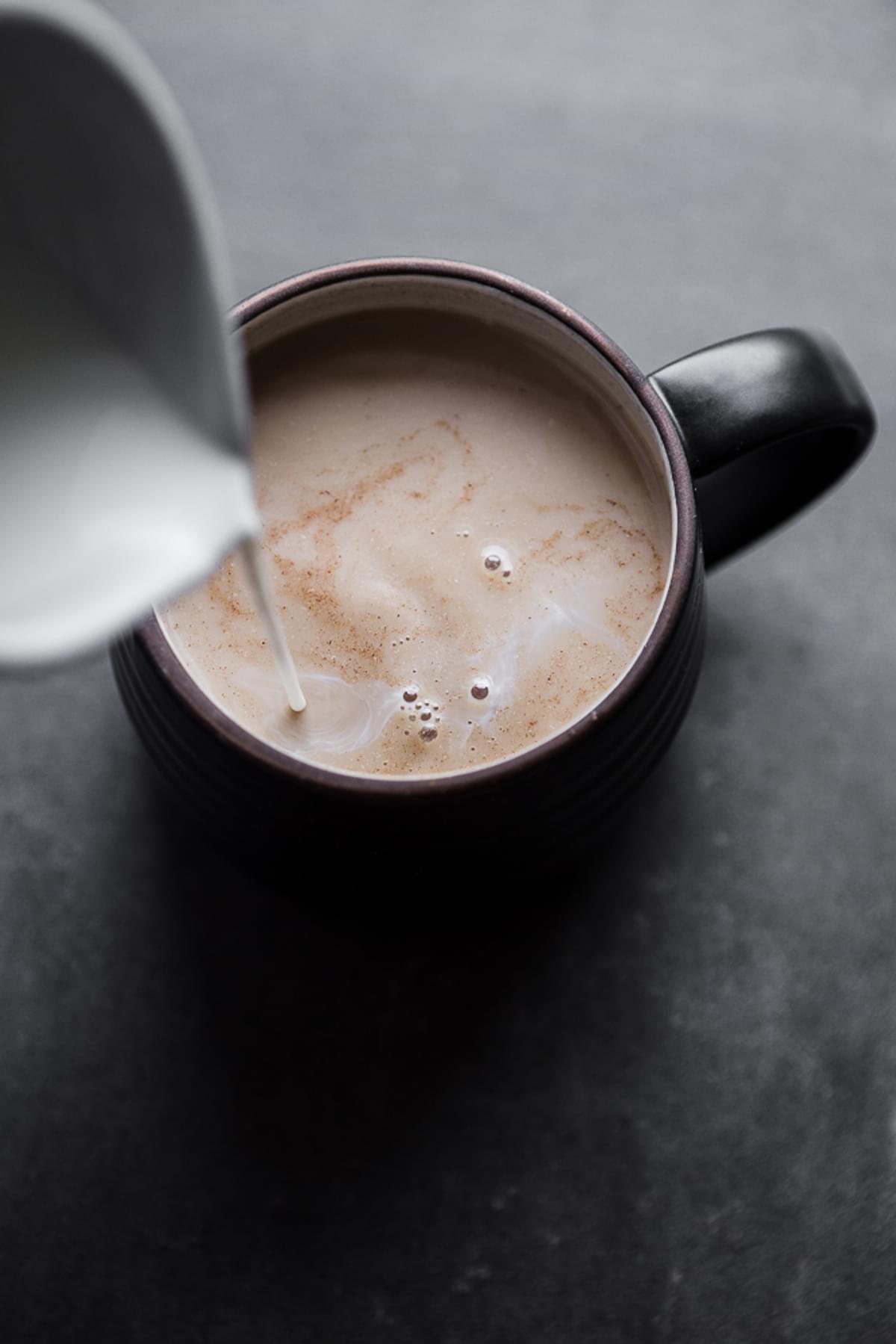 Warm milk being poured into a chai tea concentrate latte