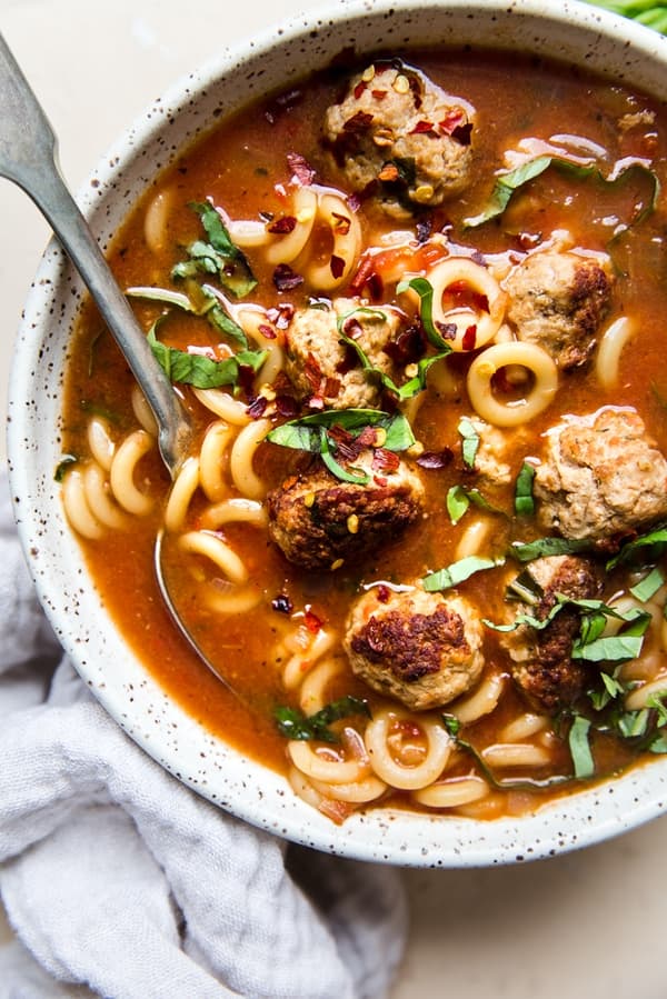 Italian tomato Meatball soup with basil and pasta in a bowl with a spoon
