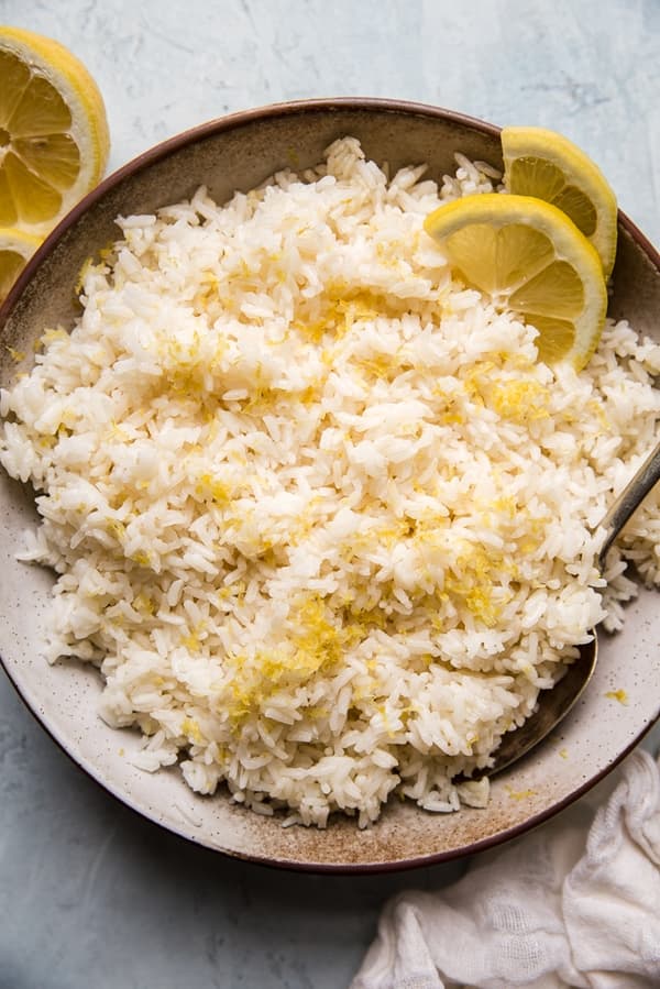a bowl of lemon rice with lemon zest with a serving spoon