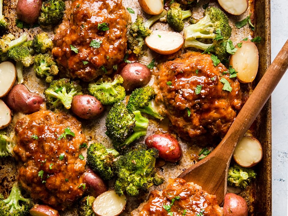 6 Mini Italian Style meat loafs on a sheet pan with broccoli and roasted potatoes.