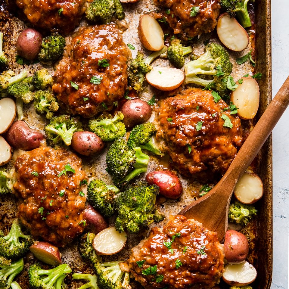 6 Mini Italian Style meat loafs on a sheet pan with broccoli and roasted potatoes.