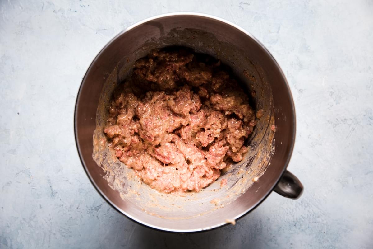 ground beef and sausage combined with eggs, milk, spices and breadcrumbs in a large metal mixing bowl