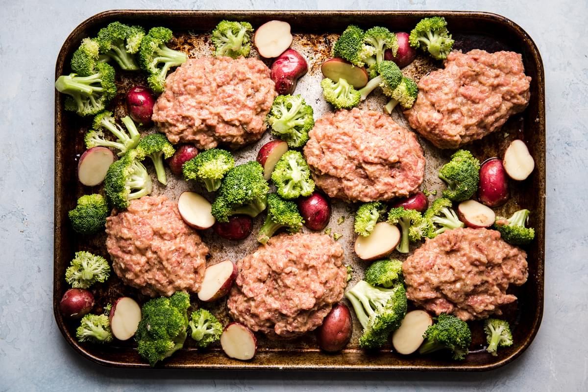 sheet pan with baby potatoes, broccoli and 6 raw meatloaf patties