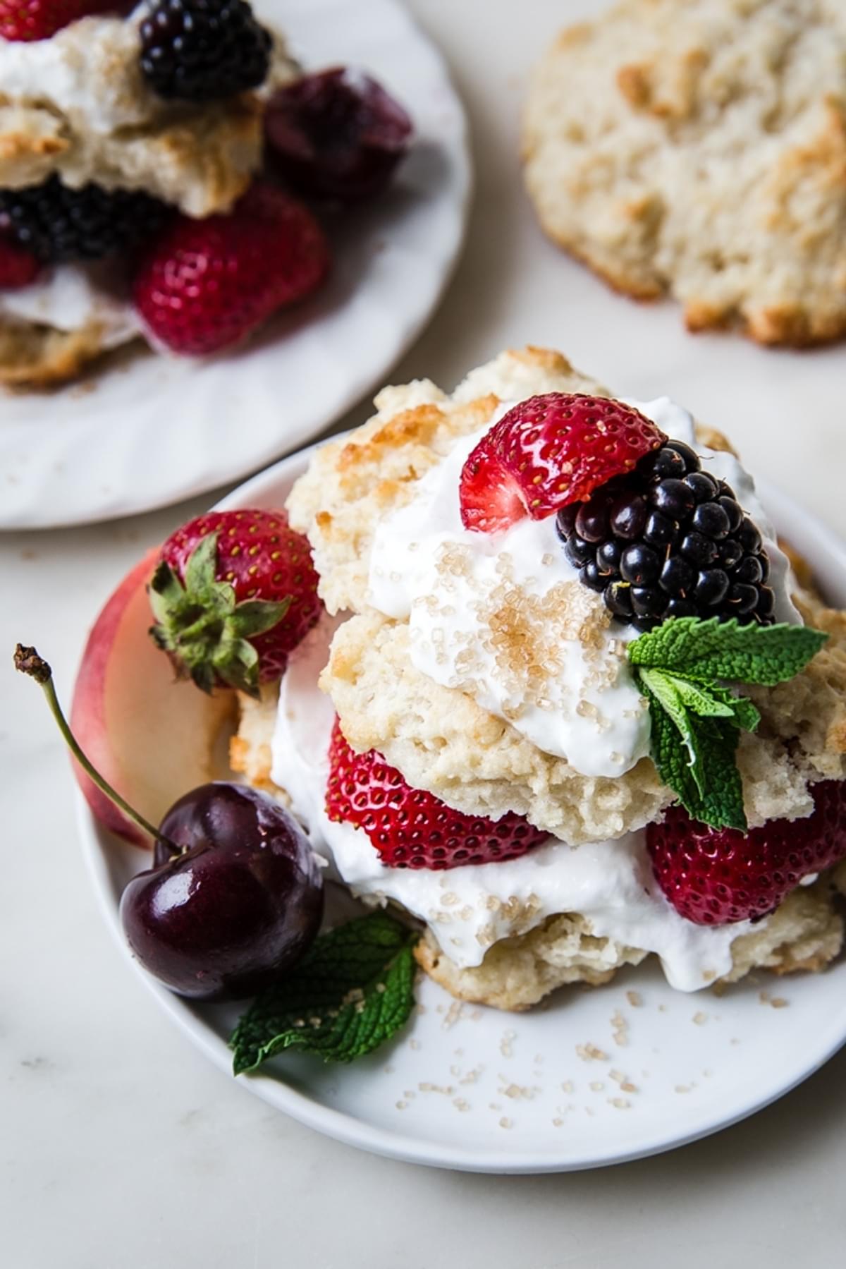 Mixed berry shortcake with whipped cream on glass plates