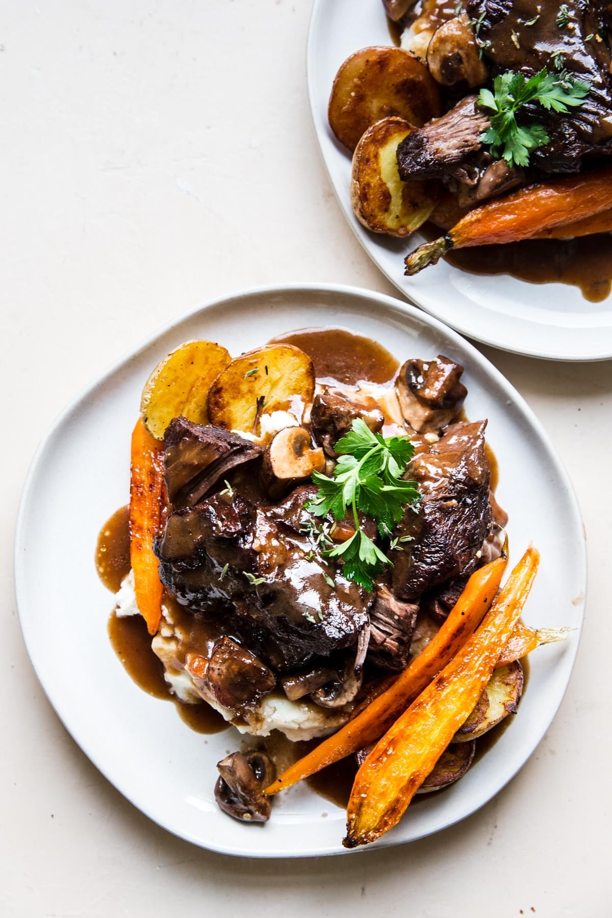 wine braised beef over mashed potatoes with roasted carrots on a plate