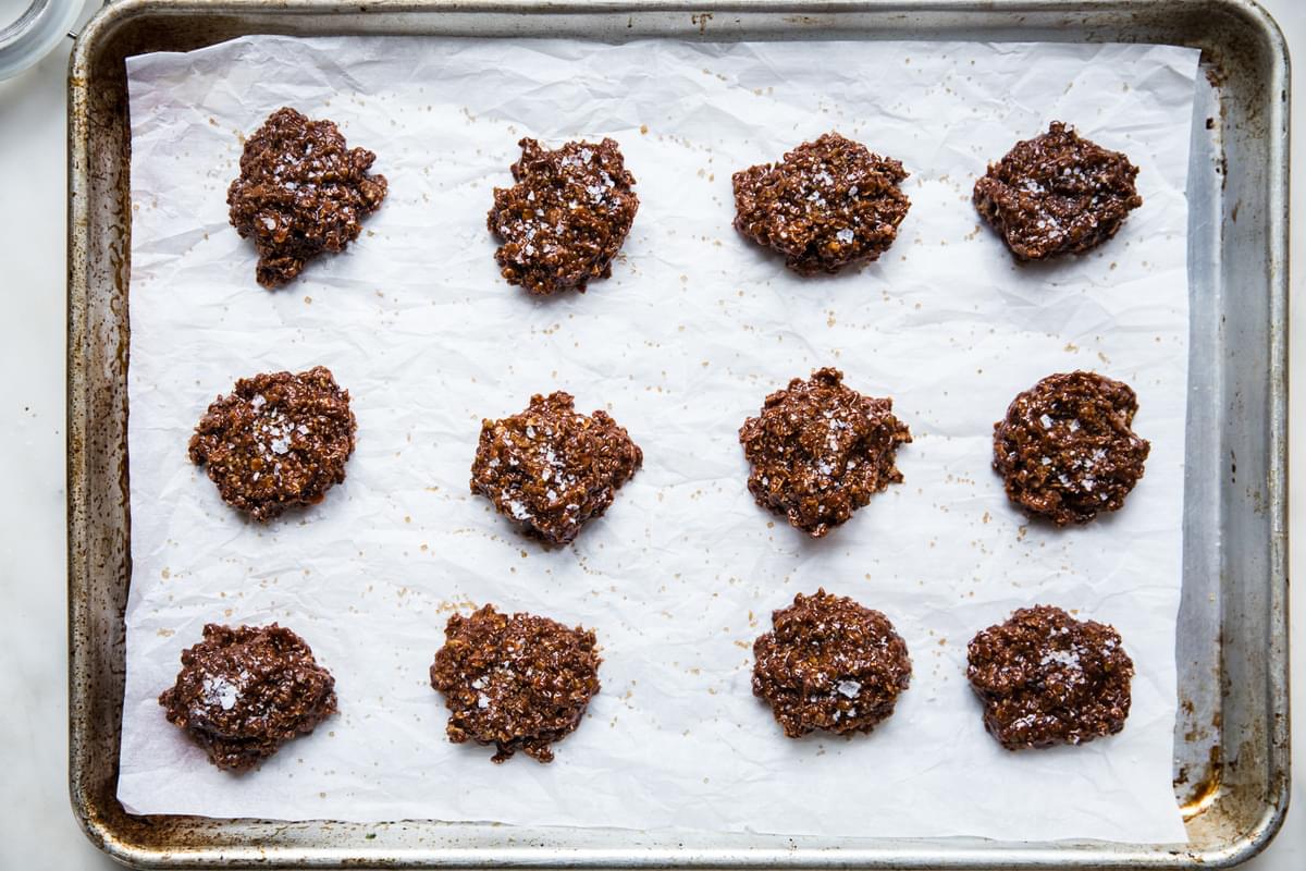 peanut butter and chocolatey no-bake cookies on a parchment lined baking sheet topped with flaky sea salt and raw sugar