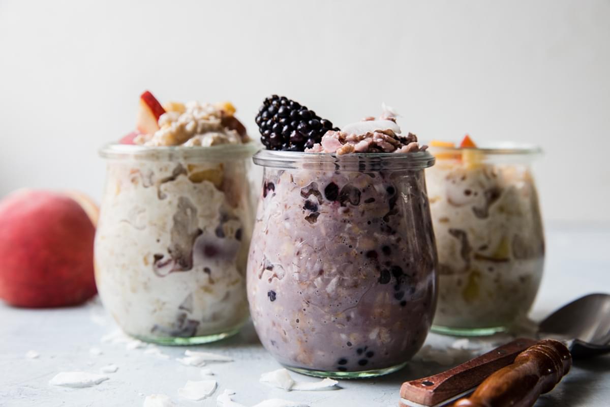 Jars of overnight oats topped with blackberries and peaches