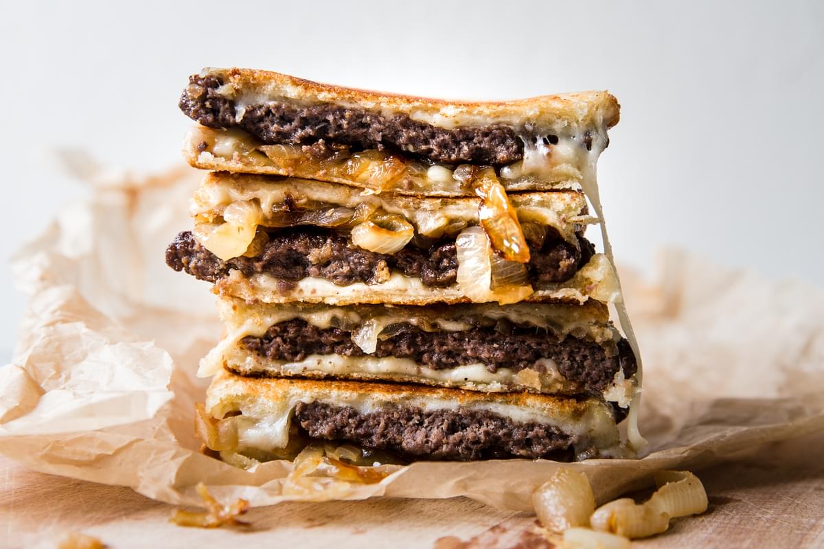 a patty melt stacked made with sourdough bread, caramelized onions, swiss cheese and mayo