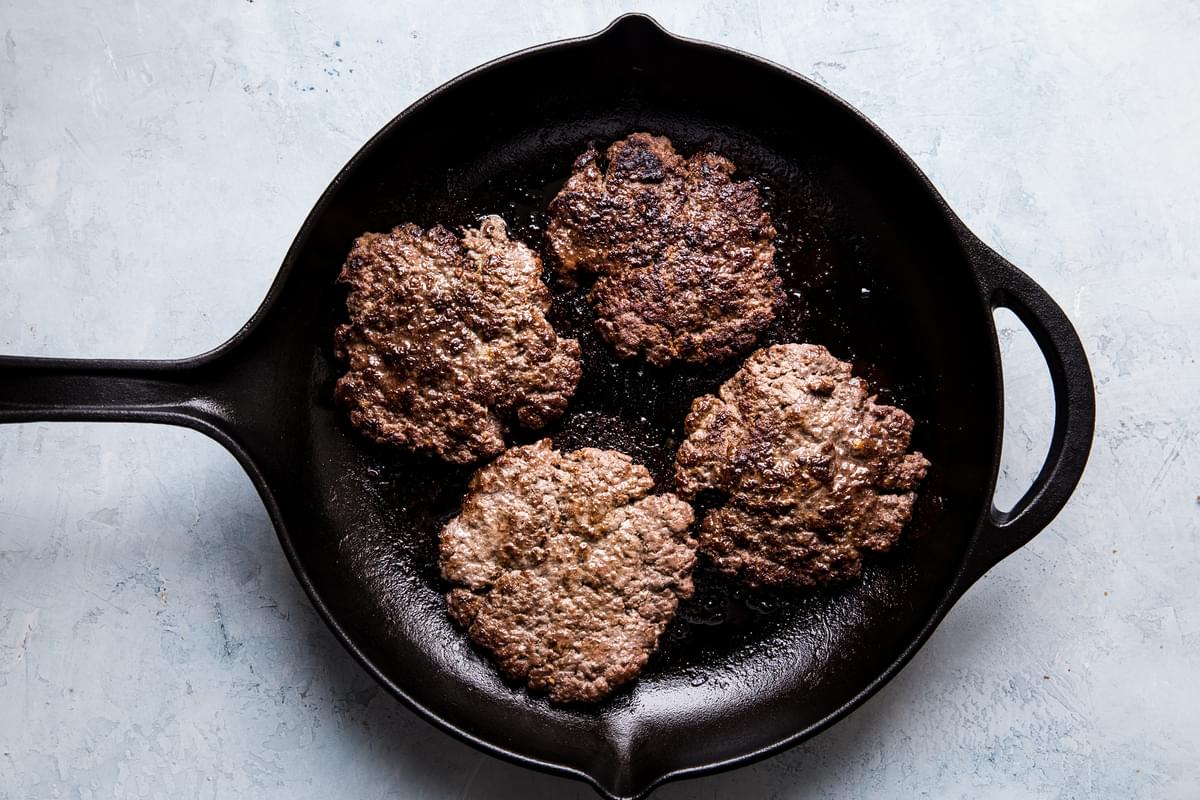 ground beef patties in a cast iron skillet