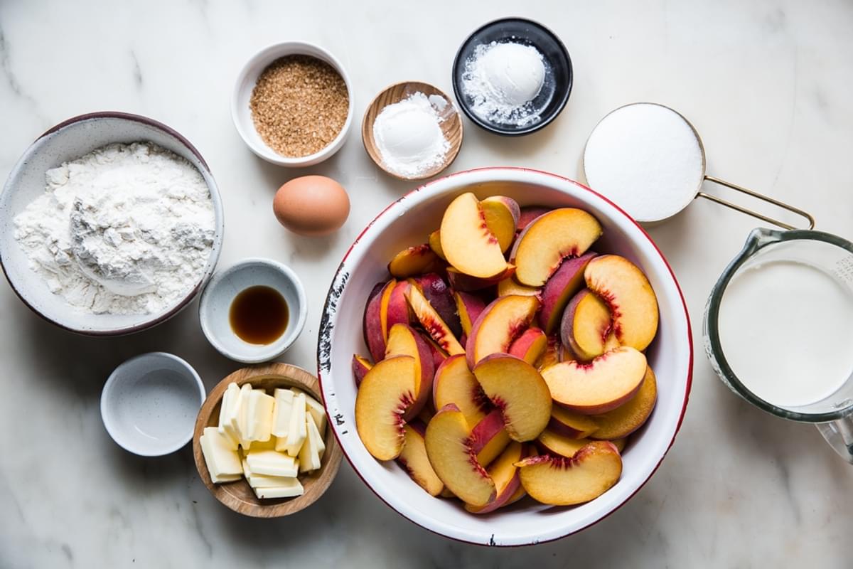 ingredients laid out for peach cobbler, butter, flour, vanilla, cream, sugar, egg