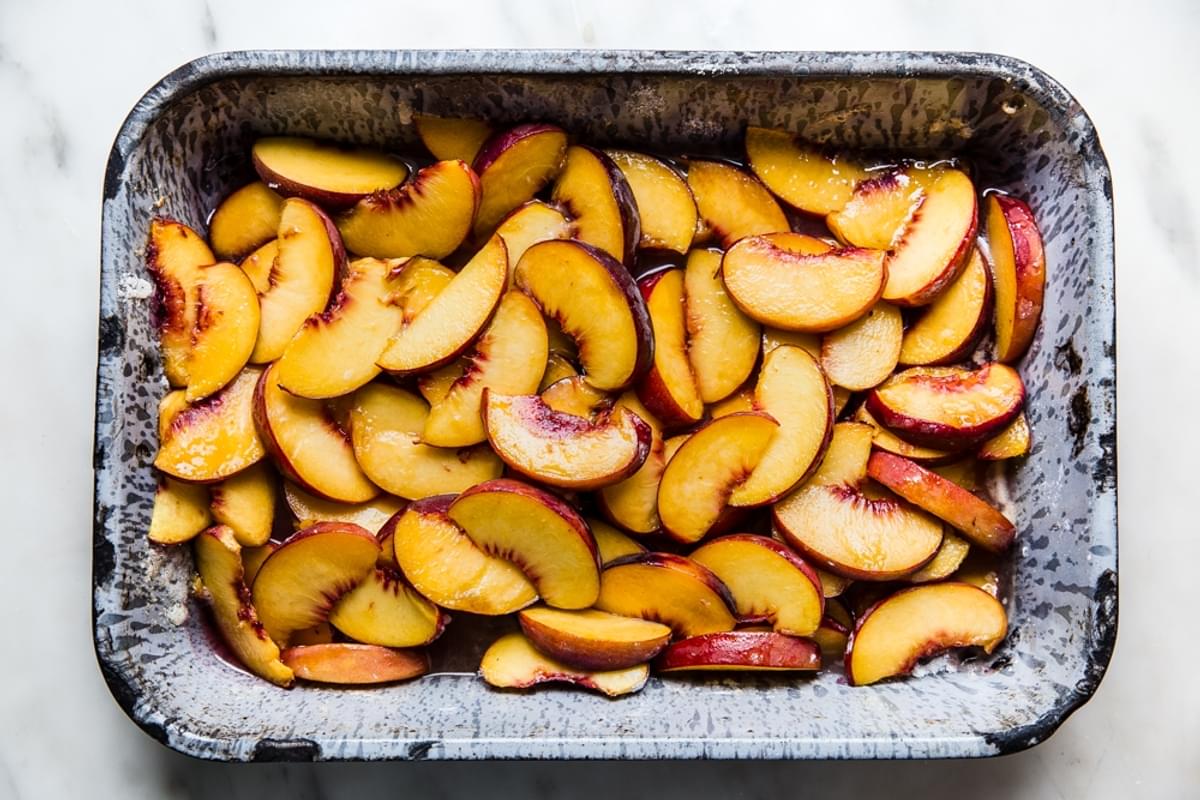 cooked peaches in a baking tin with sugar