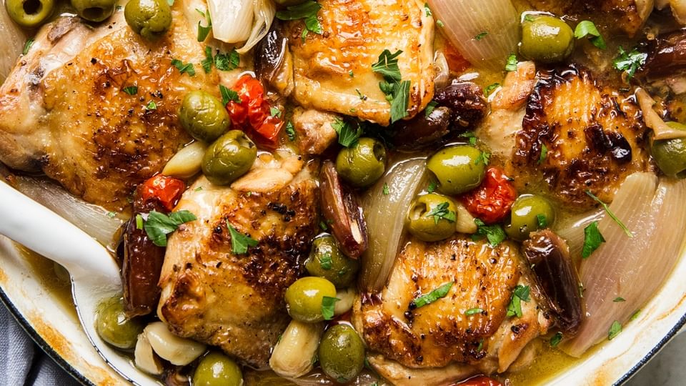 chicken Provençal with green and black olives, tomatoes, shallots, and white wine in a large braising pot