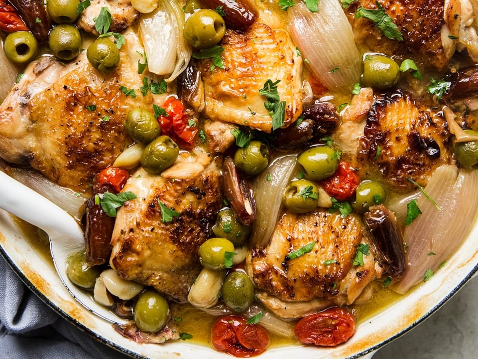 chicken Provençal with green and black olives, tomatoes, shallots, and white wine in a large braising pot